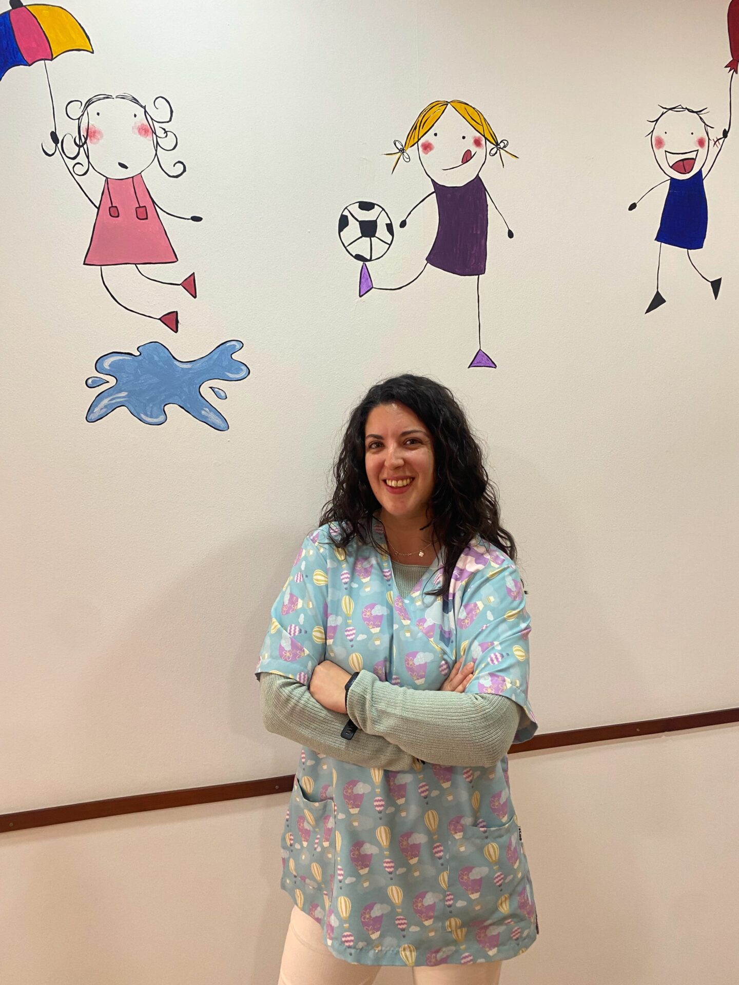 Marta Díaz en el espacio de atención infantil, junto a un mural de colores