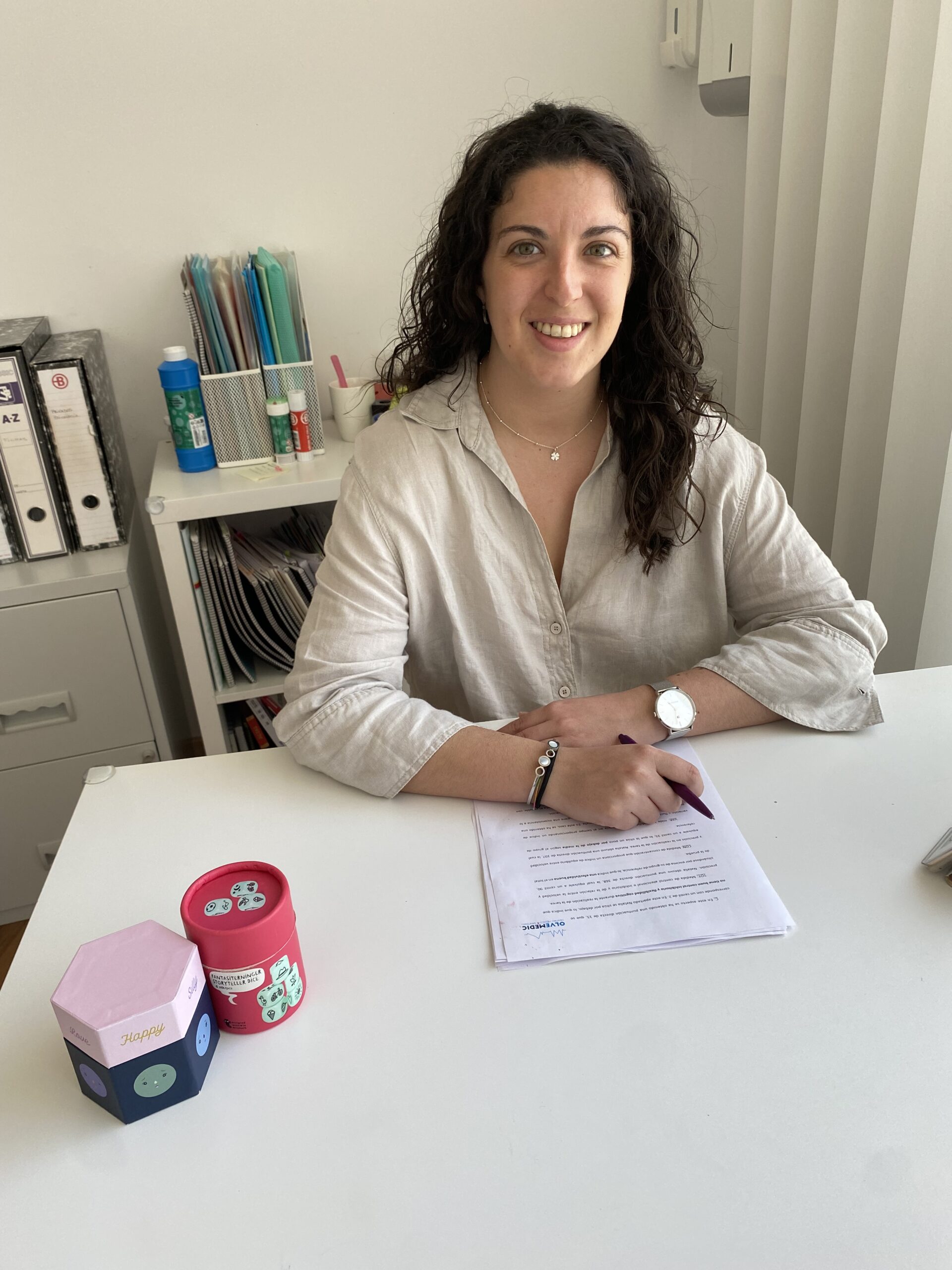 Marta Díaz sonriendo en su consulta, sentada junto a su mesa